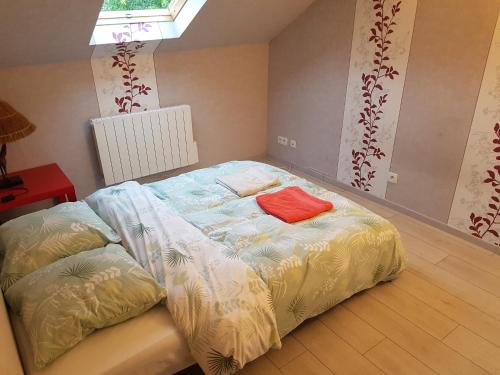 a bed in a room with a red pillow on it at Dépendance privative avec jardin à 22 mn de Paris in Savigny-sur-Orge