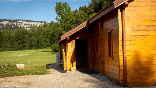 a wooden cabin with a door open in a field at Les Jardins du Hérisson Chalet 2 in Bonlieu