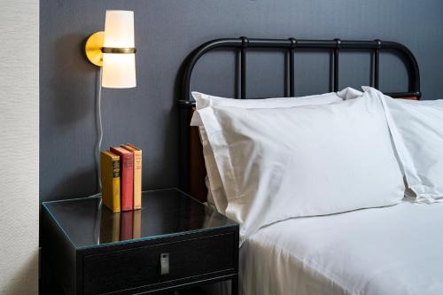 a bed with a side table with a lamp and books at Copley Square Hotel in Boston