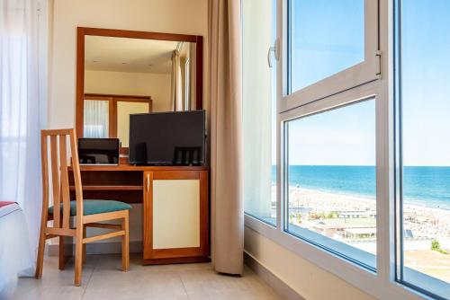 a room with a desk with a television and a window at Hotel Adria in Milano Marittima