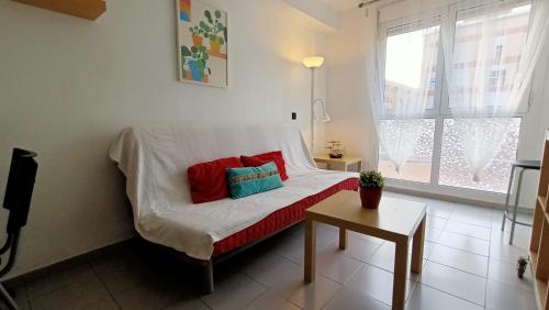 a white bed with red and blue pillows in a room at Alquilaencanarias-Medano, Cabezo beach & pool in El Médano