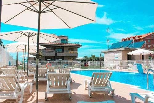 un grupo de sillas y sombrillas junto a una piscina en Apartamentos Santa María, en Sanxenxo