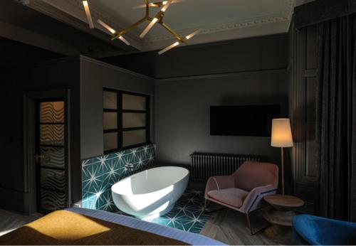 a bedroom with a white tub and a chair at Boutique 50 in Glasgow