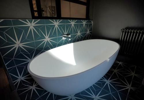 a white bath tub in a bathroom with blue tiles at Boutique 50 in Glasgow