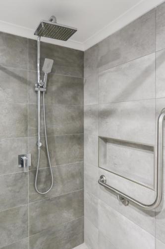 a shower with a shower head in a bathroom at Crown Apartments in Merimbula