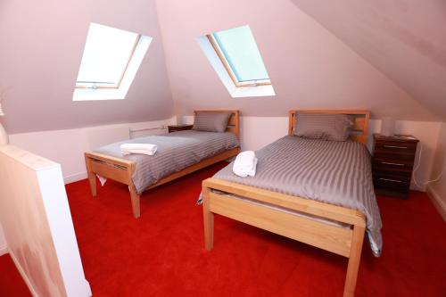 2 Betten in einem Dachzimmer mit 2 Fenstern in der Unterkunft Strathbungo Studios in Glasgow