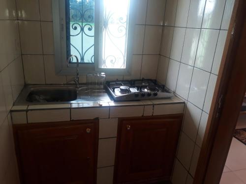 une cuisine avec évier et cuisinière ainsi qu'une fenêtre dans l'établissement NPANGOU APPART, à Kribi