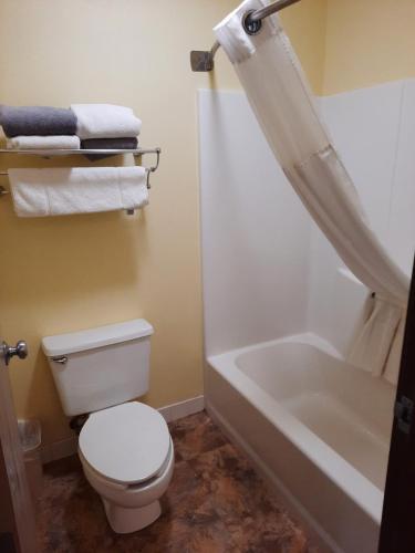 a bathroom with a toilet and a bathtub and towels at Horse Creek Inn in McCook