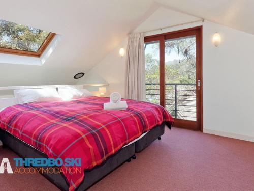 a bedroom with a bed with a red blanket at Mosswood 1 in Thredbo