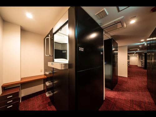 a bathroom with a black door and a mirror at Capsule Plus Yokohama Sauna & Capsule in Yokohama