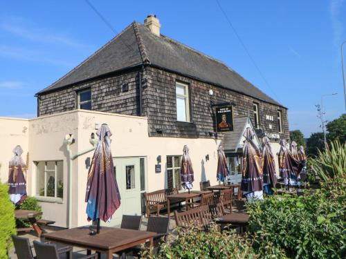 a building with tables and umbrellas in front of it at Rosewood Cottage in Durham