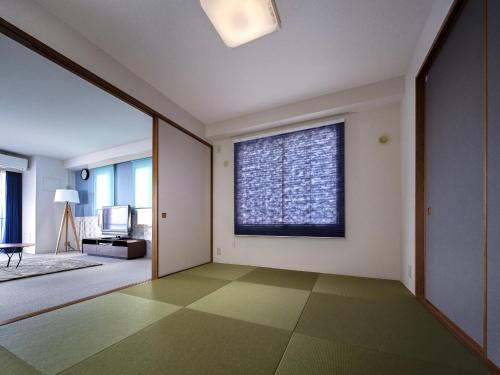 a living room with a large window and green flooring at Hotel Village Izukogen in Ito