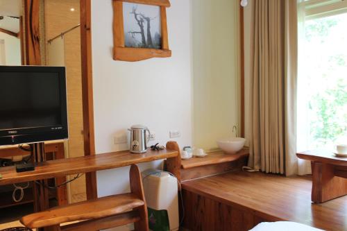 a living room with a tv and a desk with a television at Shangrila Leisure Farm in Dongshan