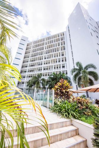 a building with stairs and palm trees in front of it at Lanai Riverside Apartments in Mackay