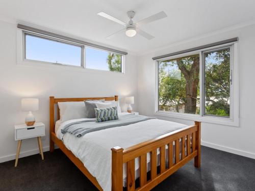 a bedroom with a bed and two windows at Normanby Coastal- walk to town & beach, free wifi & Netflix, all linen included. in Inverloch