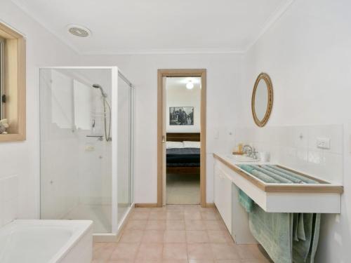 een witte badkamer met een douche en een wastafel bij Surf Side Veronica Close To Beach in Inverloch