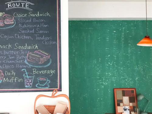 a chalkboard with a menu on a wall next to a table at ROUTE - Cafe and Petit Hostel in Nagasaki