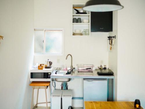 a small white kitchen with a sink and a counter at ROUTE - Cafe and Petit Hostel in Nagasaki
