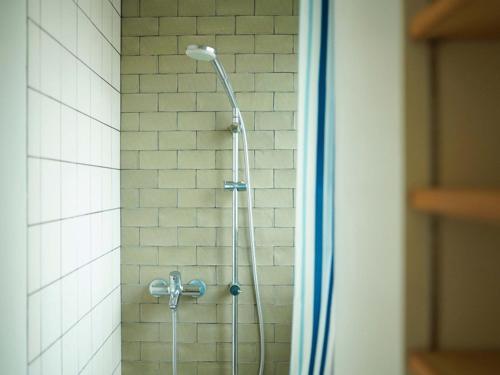 a shower with a shower head in a bathroom at ROUTE - Cafe and Petit Hostel in Nagasaki