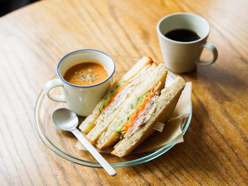 a sandwich on a plate next to two cups of coffee at ROUTE - Cafe and Petit Hostel in Nagasaki