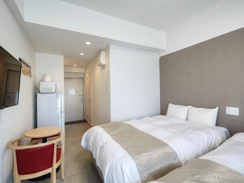 那覇市にあるBiBi Hotel NAHA KUMEのベッドルーム1室(ベッド2台、テーブル、冷蔵庫付)