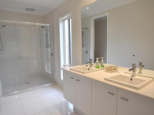 a white bathroom with two sinks and a shower at The Haven in Inverloch