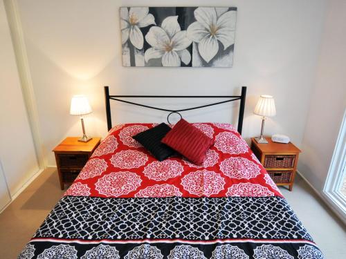 een slaapkamer met een rood en wit bed met 2 lampen bij Waves on Florida in Inverloch