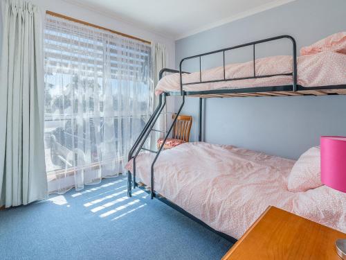 a bedroom with two bunk beds and a window at THE LIGHTHOUSE - SURF SIDE in Inverloch