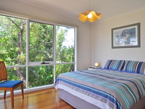 a bedroom with a bed and a large window at Scarborough Serenity in Inverloch