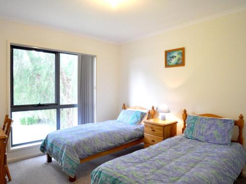 a bedroom with two beds and a window at Ridge End Inlet Side in Inverloch