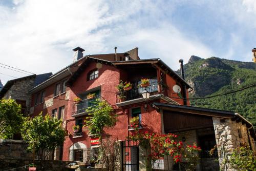 a red building with flowers in front of a mountain at La Caseta de Sastre in Eriste