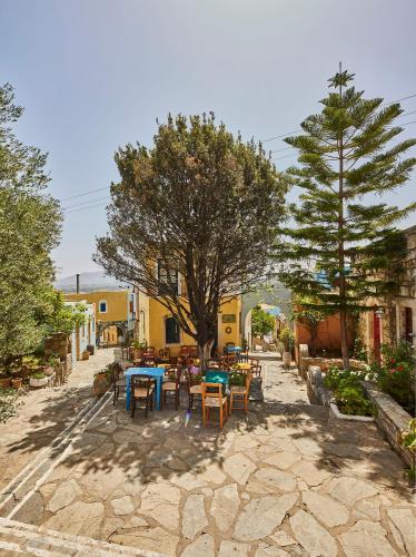 a patio with tables and chairs and a tree at Arolithos Traditional Village Hotel in Tílisos
