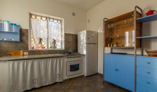 フィナーレ・リーグレにあるVilla Pierinaのキッチン(青いキャビネット、白い冷蔵庫付)