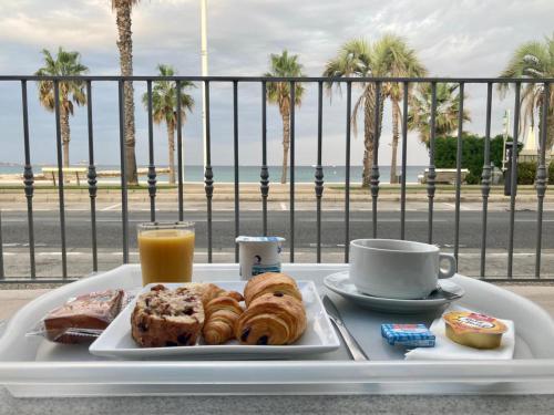 a tray with a plate of pastries and a cup of orange juice at Hôtel Bel Azur in Six-Fours-les-Plages