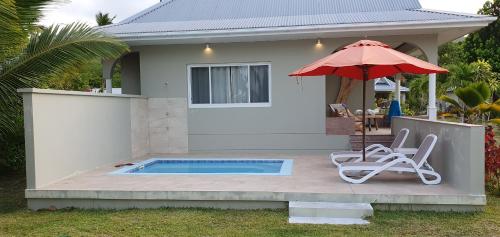 ein Haus mit einem Pool, 2 Stühlen und einem Sonnenschirm in der Unterkunft Cote d'Or Footprints in Baie Sainte Anne