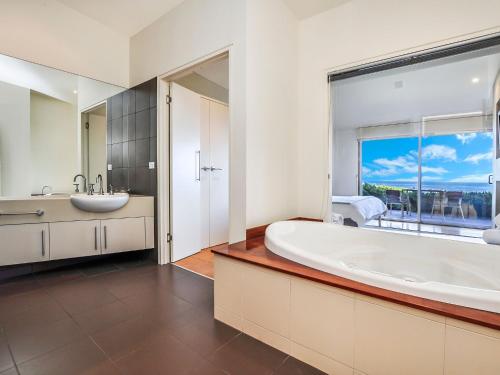 a bathroom with a tub and a sink and a window at Hearns Beachside Villa 7 in Port Fairy