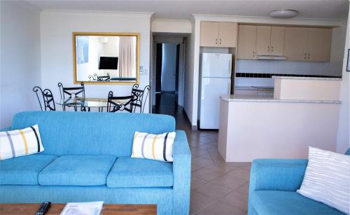 a living room with a blue couch and a kitchen at Montana Palms Resort in Gold Coast