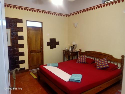 a bedroom with a bed with a red blanket and a door at Namaste Yoga Farm in Gokarna