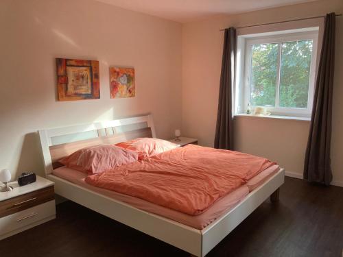 a bedroom with a bed with orange sheets and a window at Zum Eulennest in Rantrum