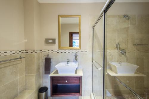 a bathroom with a sink and a shower and a mirror at Zimbali Holiday Home - 3 Baluwatu in Durban