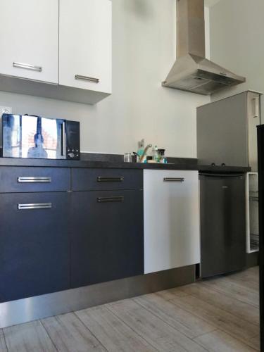 - une cuisine avec des placards noirs et blancs et une cuisinière dans l'établissement Pau hypercentre Studio, à Pau