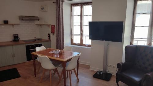 a dining room with a table and a flat screen tv at Salardine Apartments - Cosy Suite in Châlus