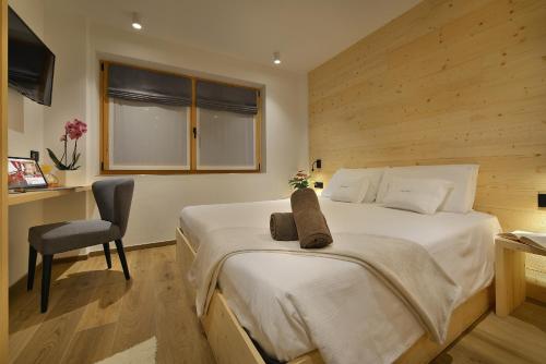 a bedroom with a large bed and a chair at Hotel Valtellina in Livigno