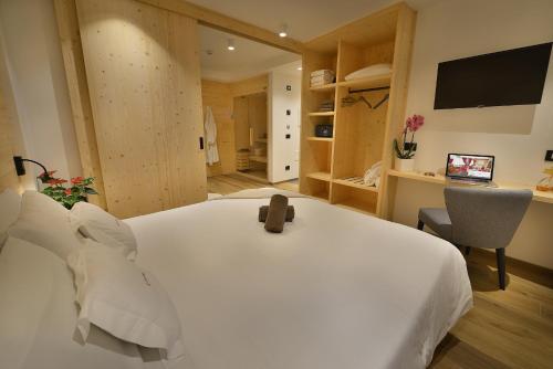 a bedroom with a white bed with a teddy bear on it at Hotel Valtellina in Livigno