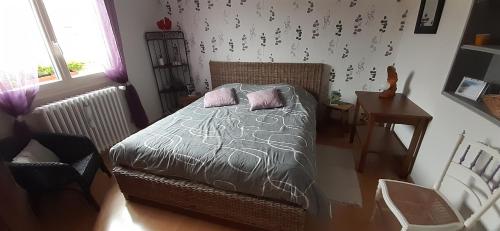 Un dormitorio con una cama con almohadas rosas. en Chez Evelyne chambre d'hôtes chez l'habitant, en Verdún