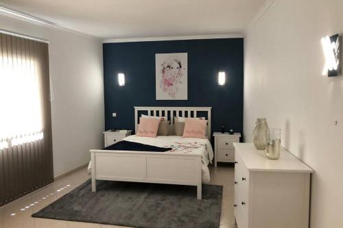 a bedroom with a white bed and a blue wall at Le Modern' in Albufeira
