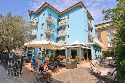 personnes assises sur des chaises devant un bâtiment bleu dans l'établissement Hotel La Perla, à Bellaria-Igea Marina