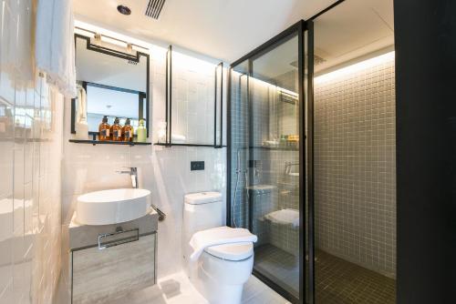 a bathroom with a toilet and a sink and a shower at KēSa House, The Unlimited Collection managed by The Ascott Limited in Singapore