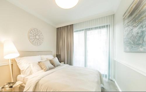 a white bedroom with a bed and a window at Apartament 117 - Rezydencja Niechorze in Niechorze