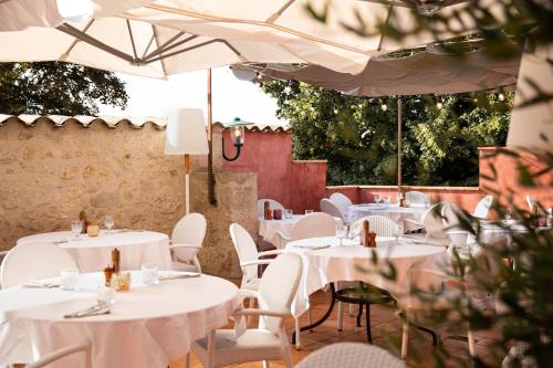 a restaurant with white tables and chairs and umbrellas at Le Square in Astaffort